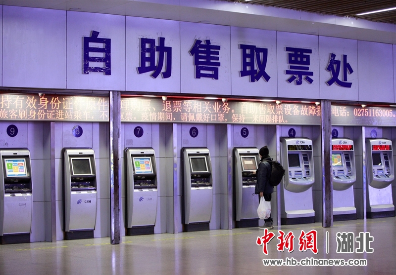 1月28日上午,在武汉武昌火车站自助售取票处,一名乘客正在取票.